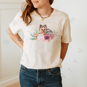 a woman standing in a room with white walls wearing an ivory (natural) tee featuring a graphic of a yorkie surrounded by flowers