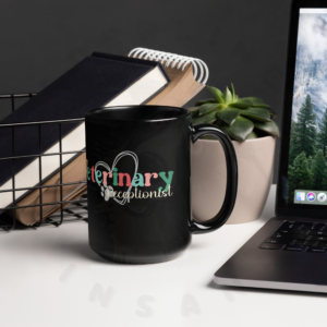 15oz black ceramic veterinary receptionist mug on a desk in front of books next to a laptop