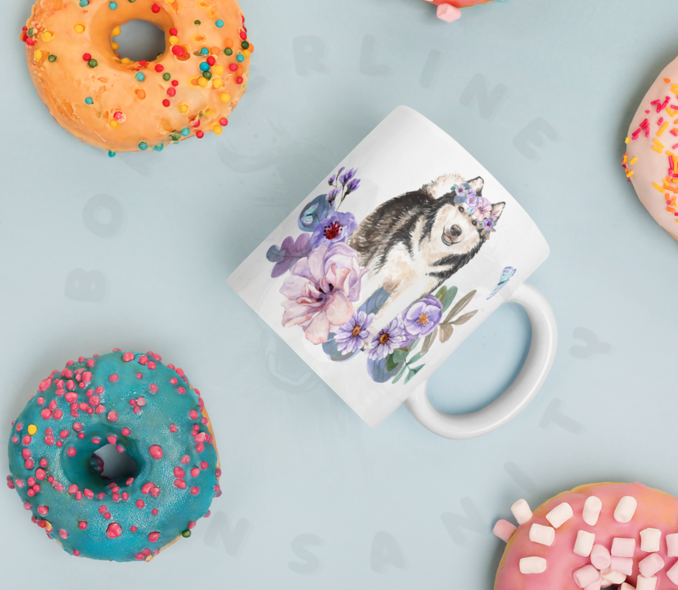 alaskan malamute in flowers mug lying on a table surrounded by colorful donuts