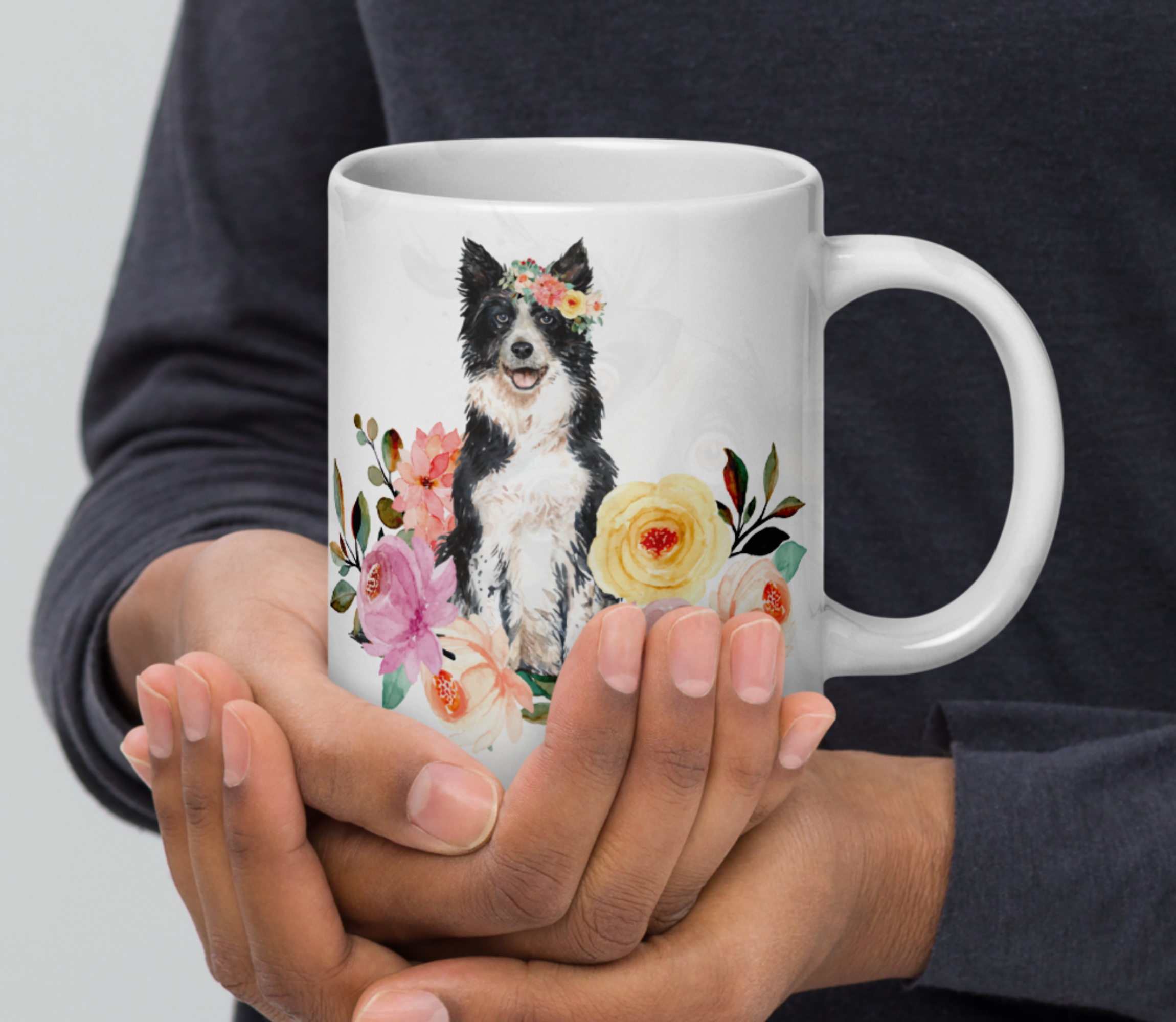 hands holding a border collie in flowers mug