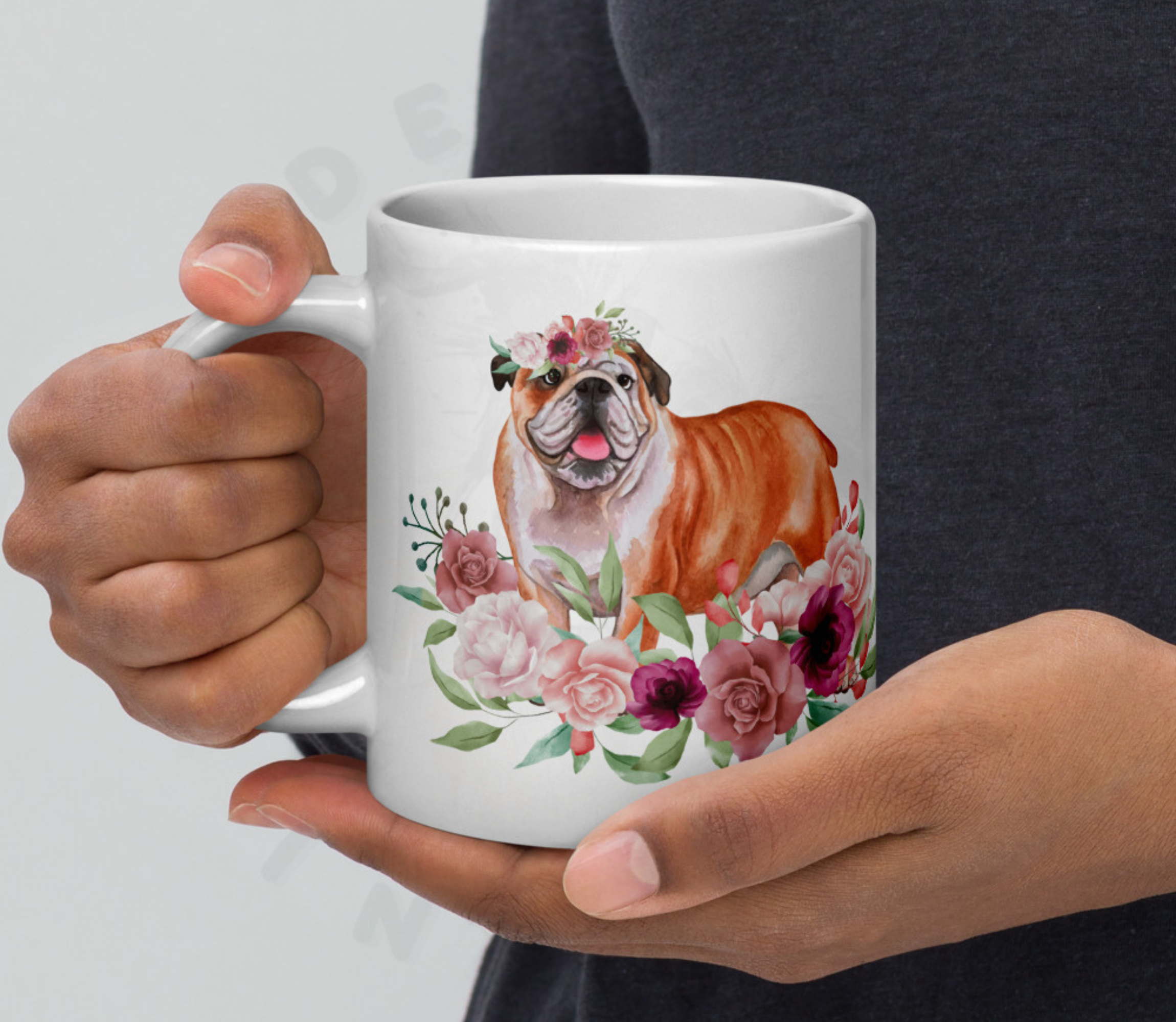 English bulldog in flowers mug held by a person wearing a blue sweater