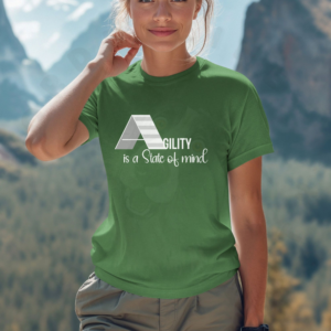 a woman standing in front of mountains wearing a agiility is a state of mind tee in leaf green