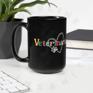 15oz black ceramic veterinarian mug on a desk in front of a plant
