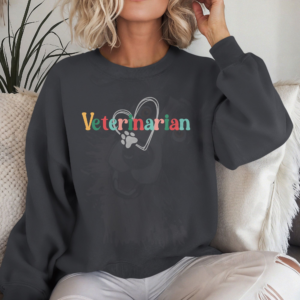 a woman on a white sofa wearing a charcoal sweatshirt with a colorful veterinarian design with a heart and pawprint