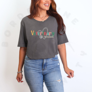 a woman standing in front of a white background wearing an asphalt veterinary assistant tee with a heart and paw print