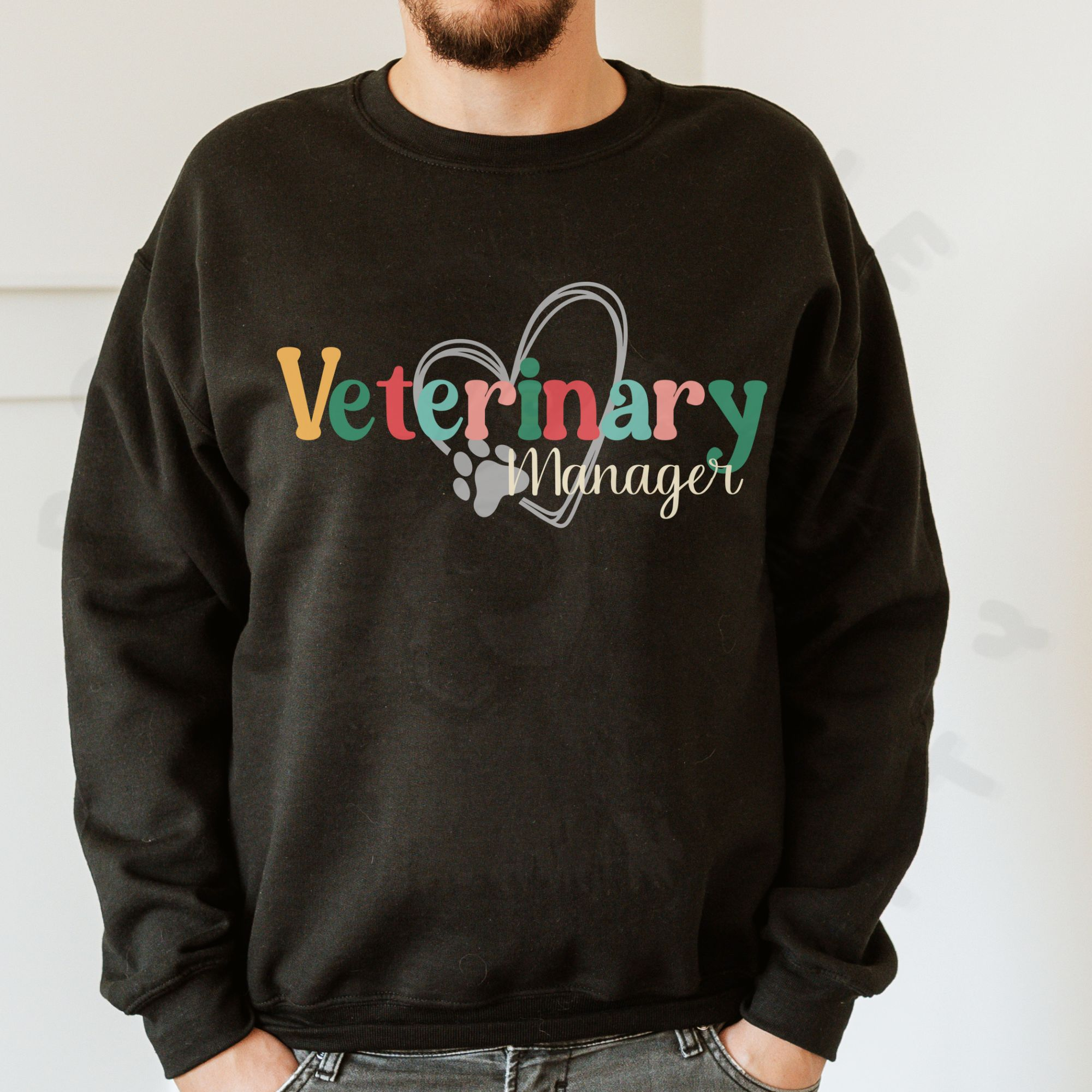 a man in front of a white background wearing a black sweatshirt with a colorful veterinary manager design with a heart and pawprint