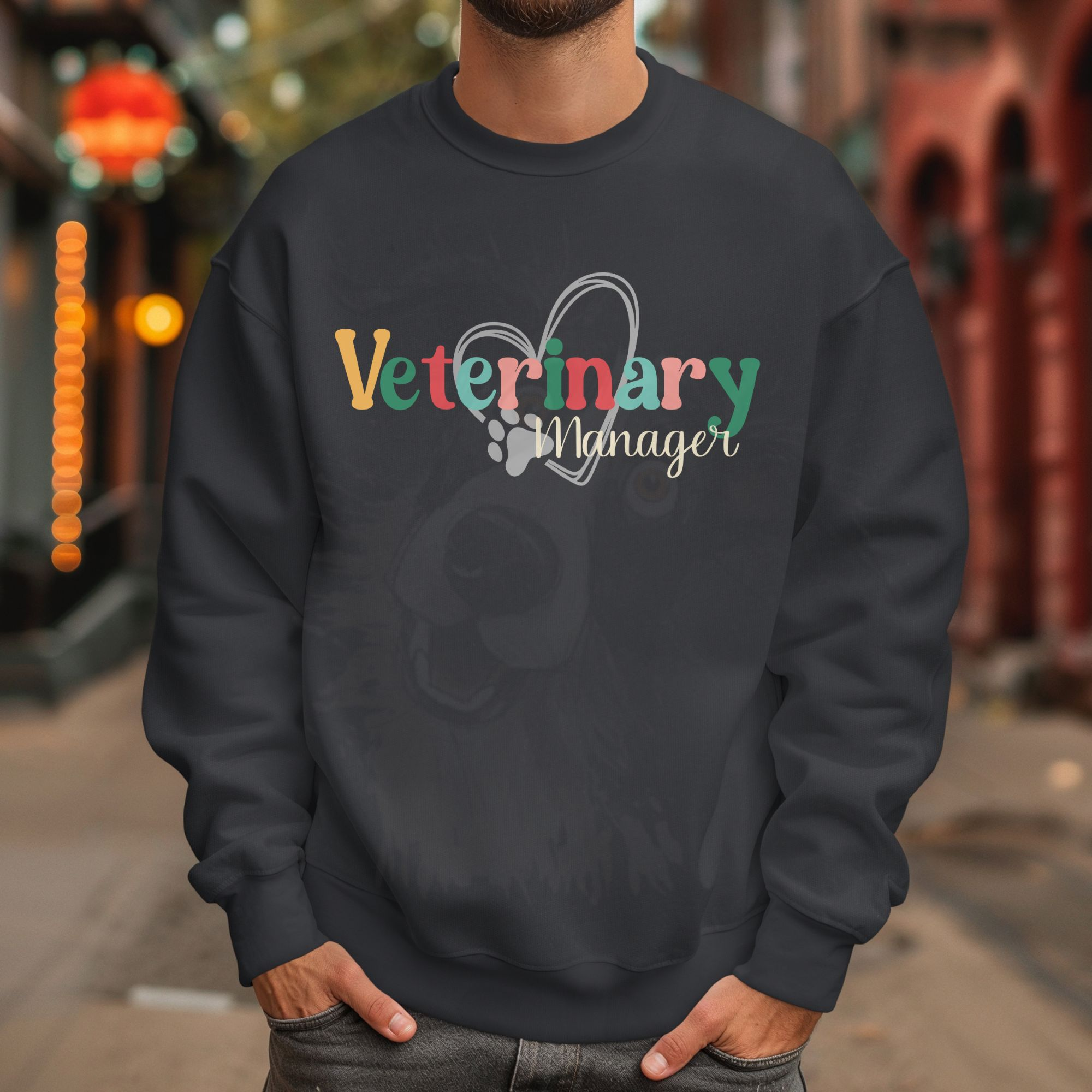 a man standing in an alley wearing a charcoal sweatshirt with a colorful veterinary manager design with a heart and pawprint