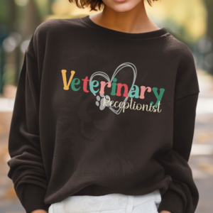 a woman standing in a woods wearing a brown sweatshirt with a colorful veterinary receptionist design with a heart and pawprint