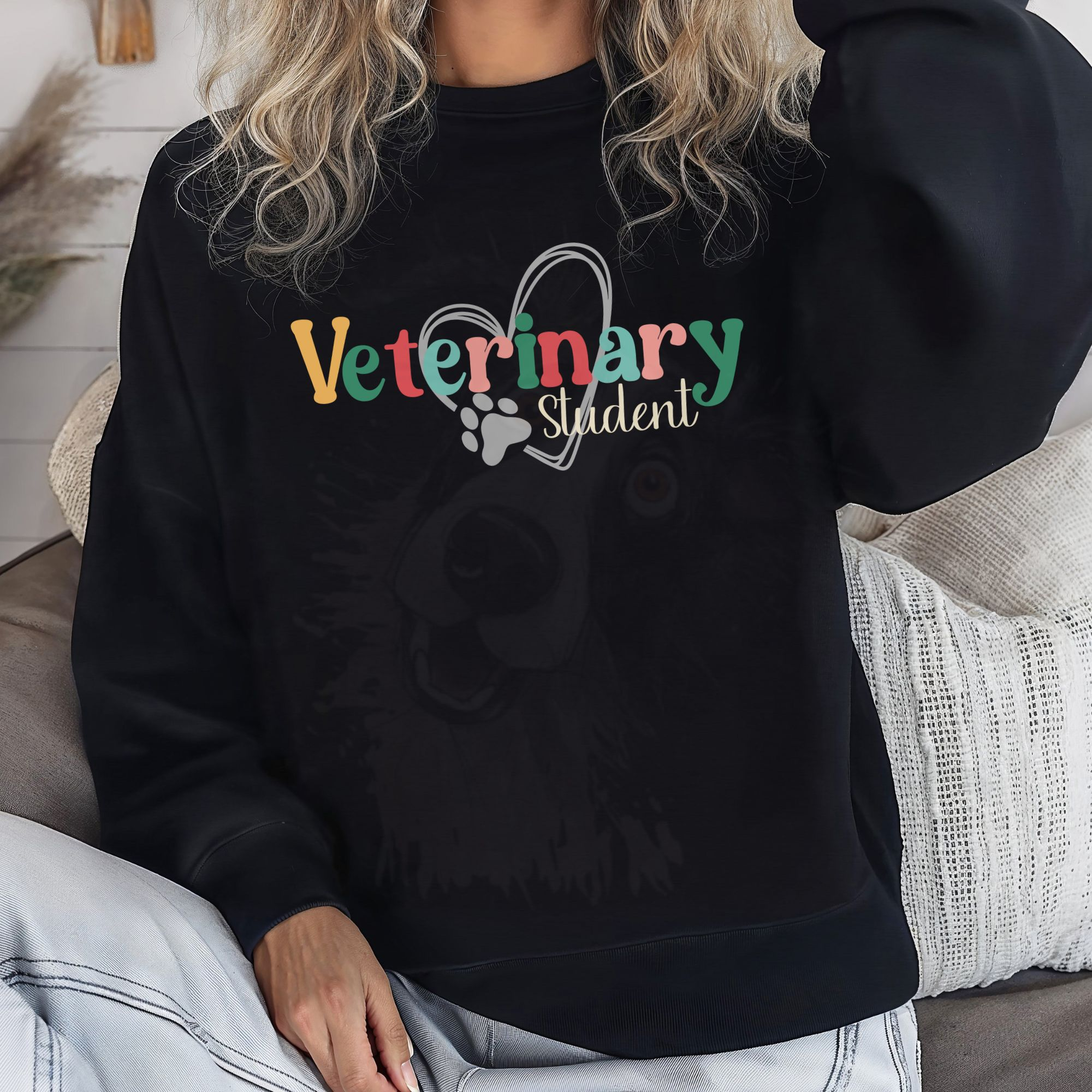 a woman in jeans wearing a black sweatshirt with a colorful veterinary student design with a heart and pawprint