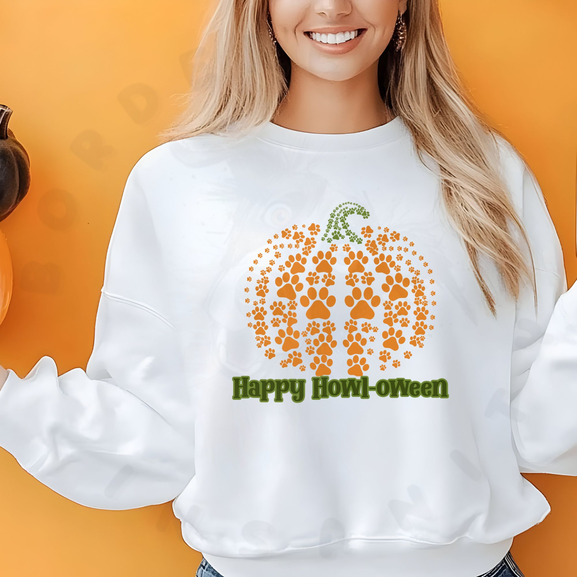 a woan standing in front of an orange background wearing a white halloween sweatshirt that says happy howl-oween below a pumpkin made up of pawprints