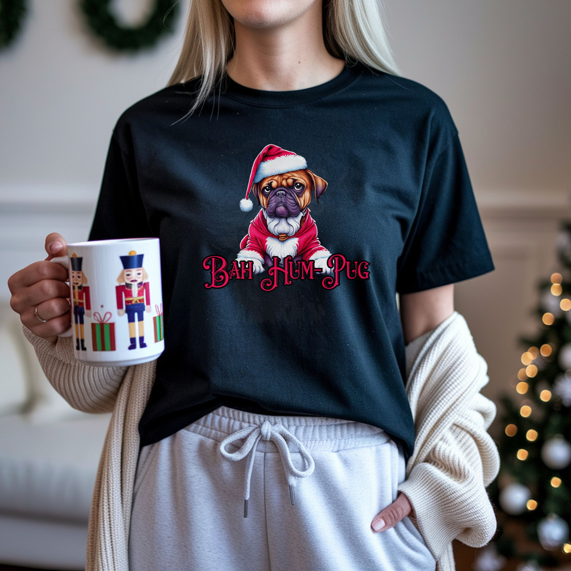 a woman standing in a room decorated for christmas holding a nutcracker mug wearing a black t-shirt that says bah hum-pug below a graphic of a grumpy pug wearing a santa suit