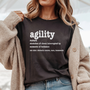 a woman wearing a tan sweater over a brown tee featuring a humorous agility definition