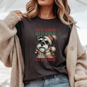 a woman wearing an oversized tan boho style sweater over a brown tee that features a schnauzer wearing a festive winter hat and scarf and the words let it schnau let it schnau let it schnau