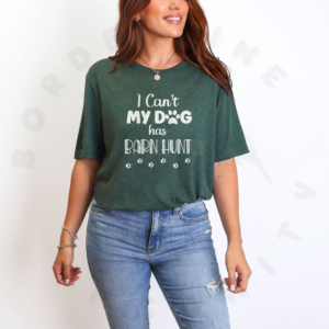a woman standing in front of a white background wearing a heather forest i can't my dog has barn hunt tee