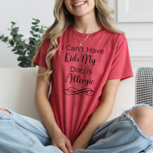 a woman sitting on a sofa wearing a heather red tee that says i can't have kids my dog is allergic