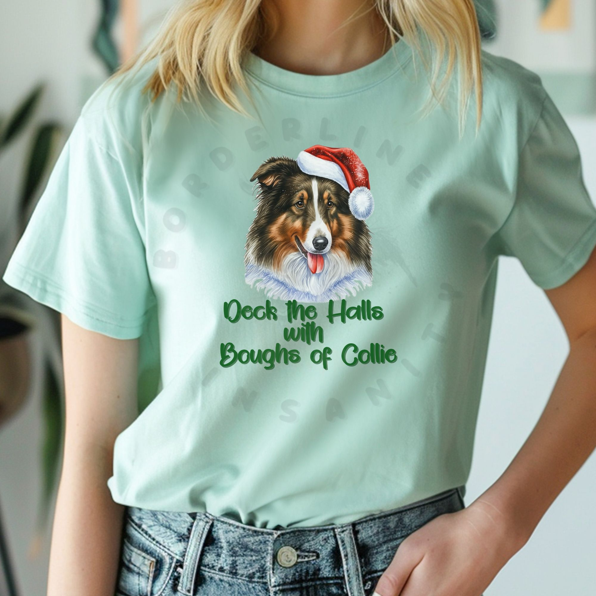 a woman wearing a mint green t-shirt that features a rough collie wearing a santa hat and says Deck the halls with boughs of collie
