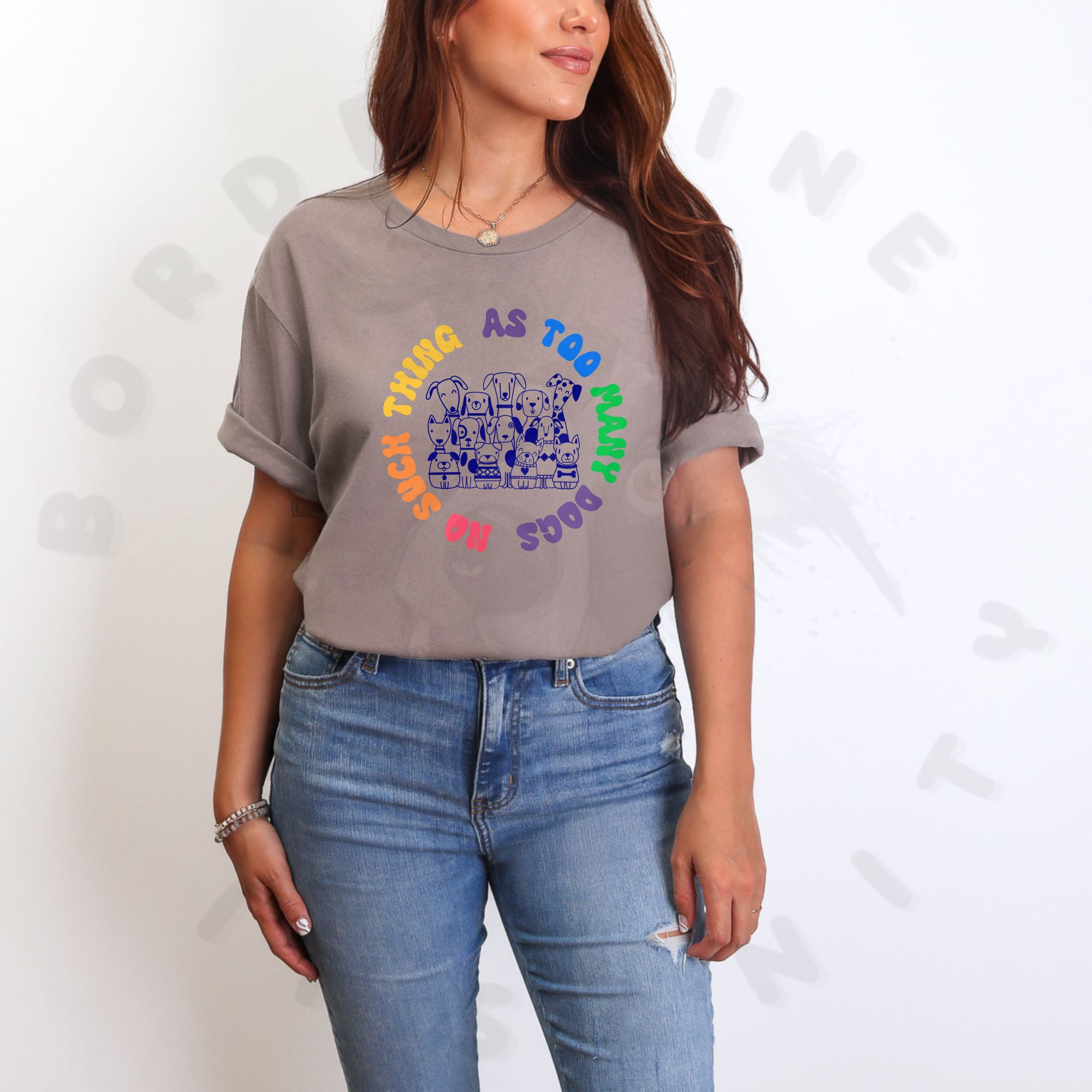 Light dusty brown shirt with illustration of many dogs and rainbow text that says “No such thing as too many dogs.”