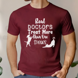 a man standing in front of a neutral background and plants wearing a cardinal t-shirt that says real doctors treat more than one species in various fonts