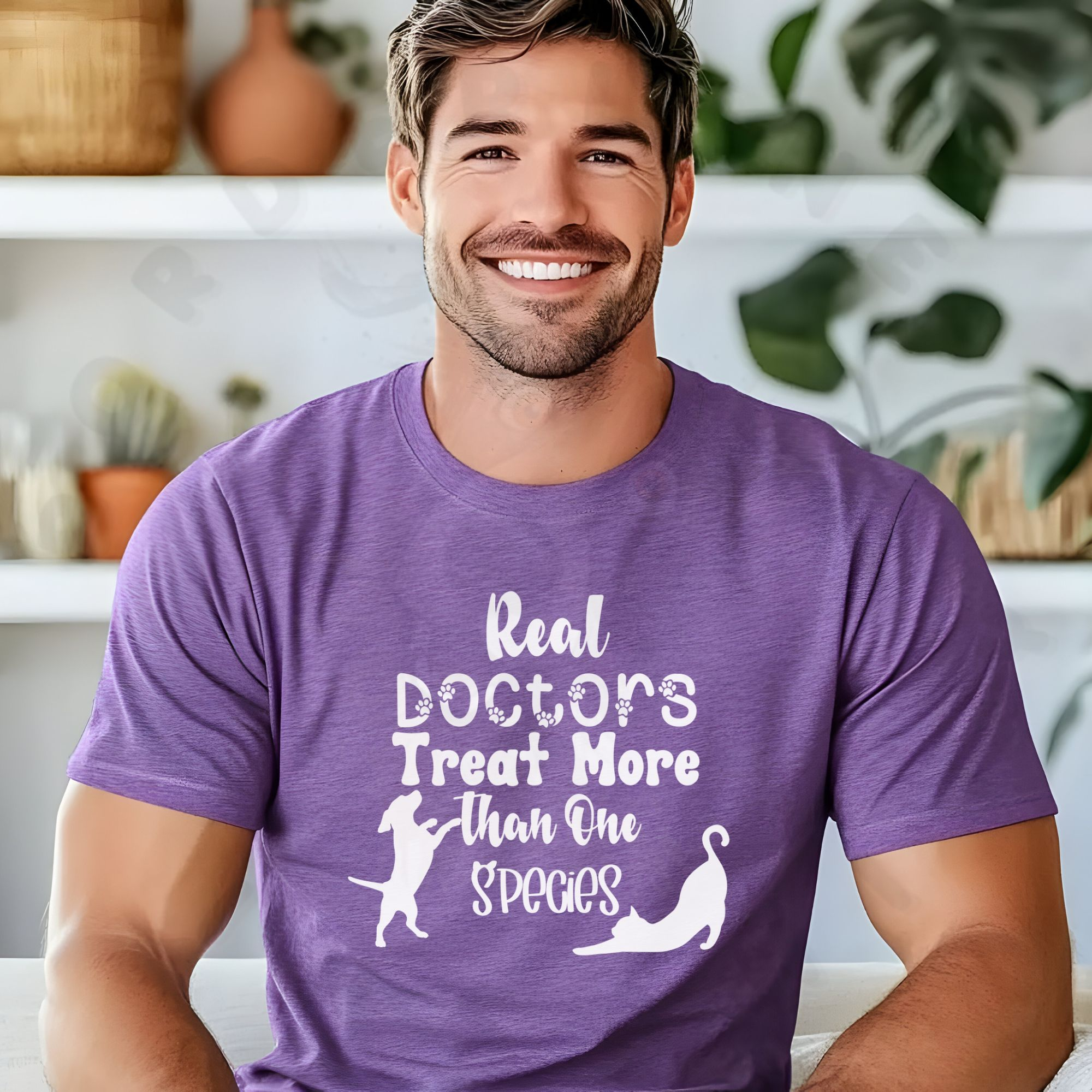 a man sitting in front of shelves with pottery and plants wearing a heather team purple t-shirt that says real doctors treat more than one species in various fonts