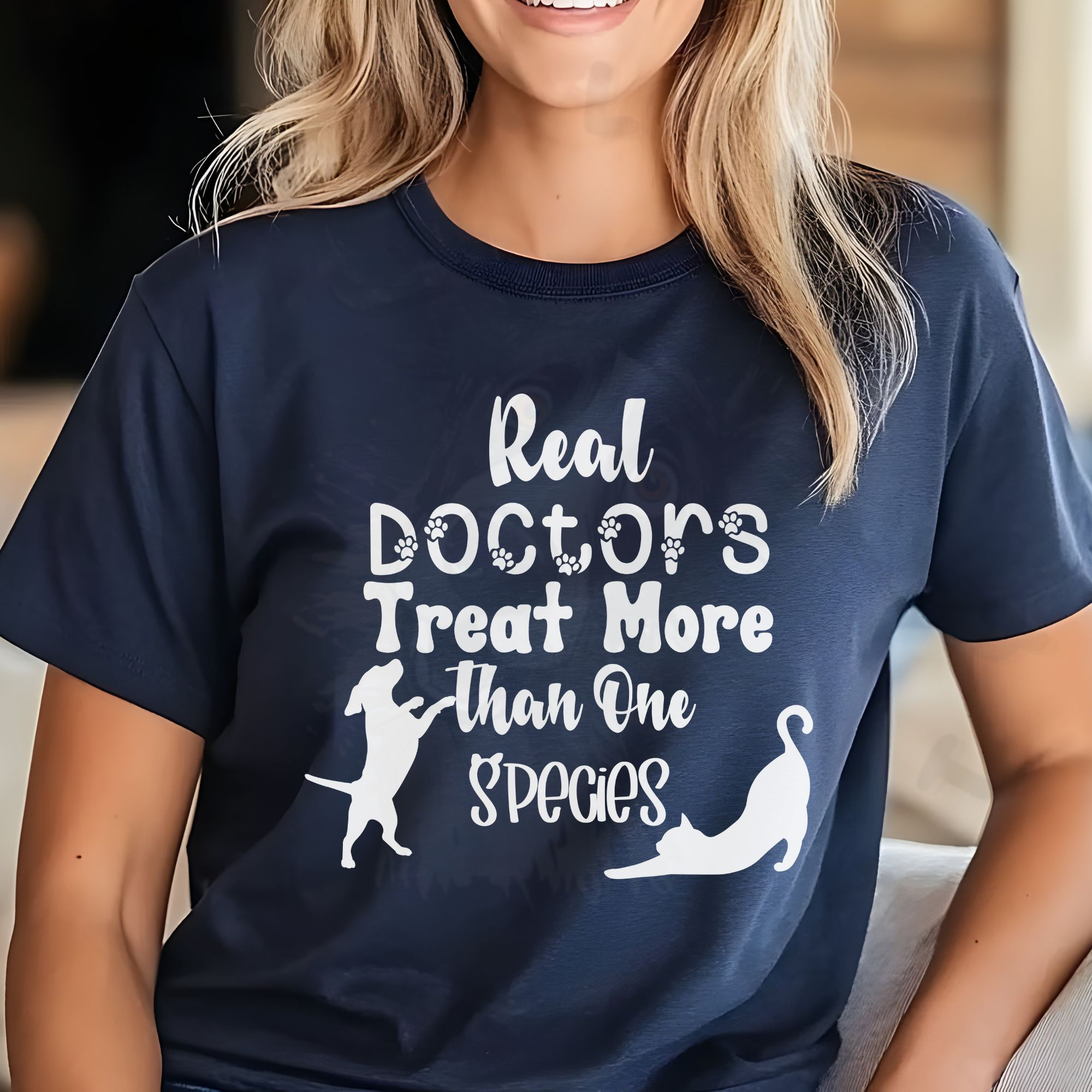 a woman wearing a navy blue t-shirt that says real doctors treat more than one species in various fonts
