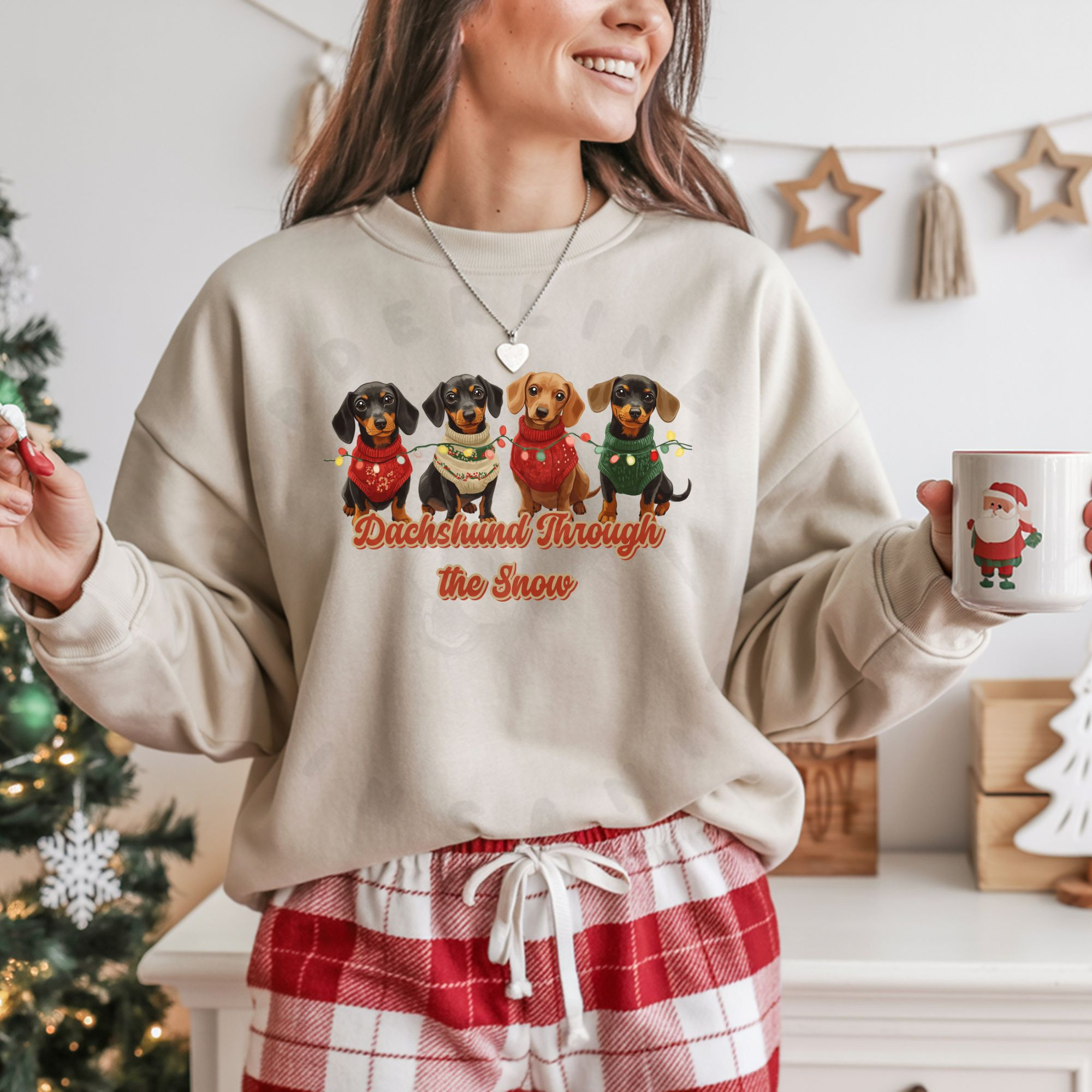 a woman holding a christmas mug wearing red plaid pajama pants and a sand dachshund through the snow sweatshirt featuring 4 dachshunds wearing christmas sweaters and tangled in christmas lights