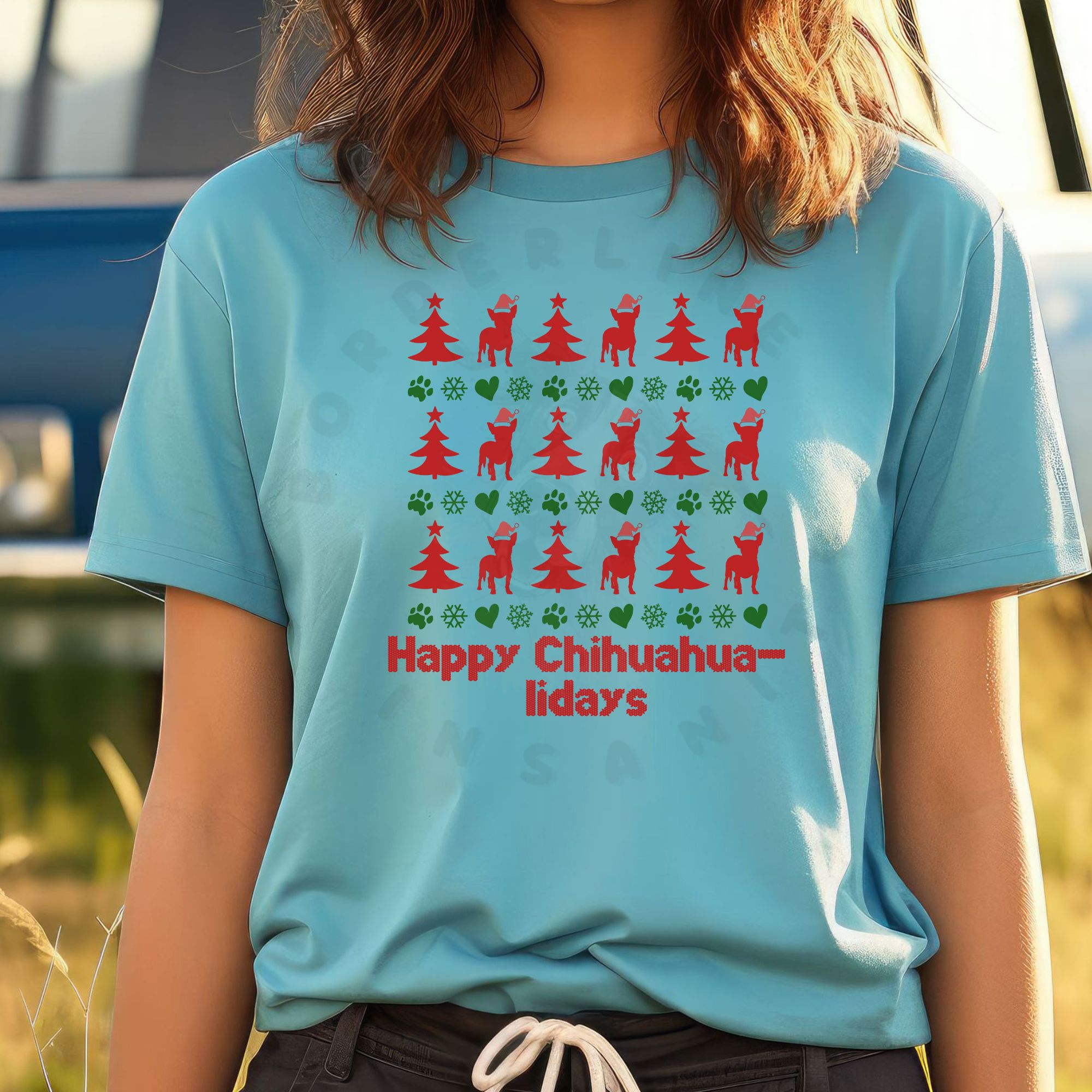 a woman standing in a field in front of a camper wearing a turquoise t-shirt designed ugly christmas sweater style with rows of red christmas trees, green snowflakes, and chihuahuas wearing santa hats.