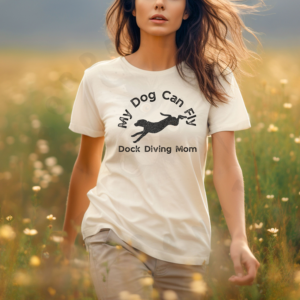 a woman standing in a field of wildflowers wearing an ivory (natural) tee that says my dog can fly dock diving mom with a silhouette of a diving dog