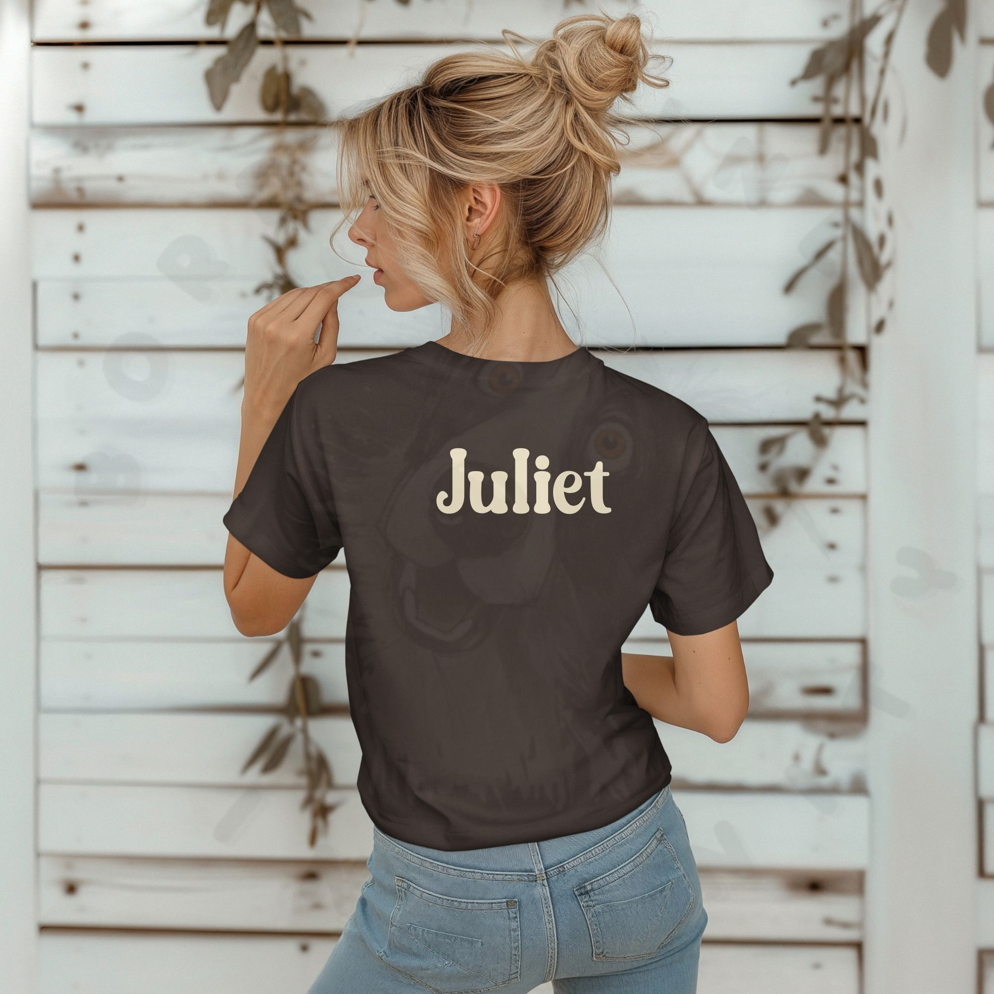 a blonde woman standing in front of a rustic looking wall with vines, wearing jeans and a brown future veterinarian tee that says her name on the back