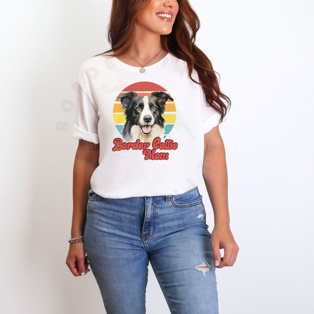 a woman standing in front of a white background wearing a white tee with a retro sunset design with a border collie that says border collie mom