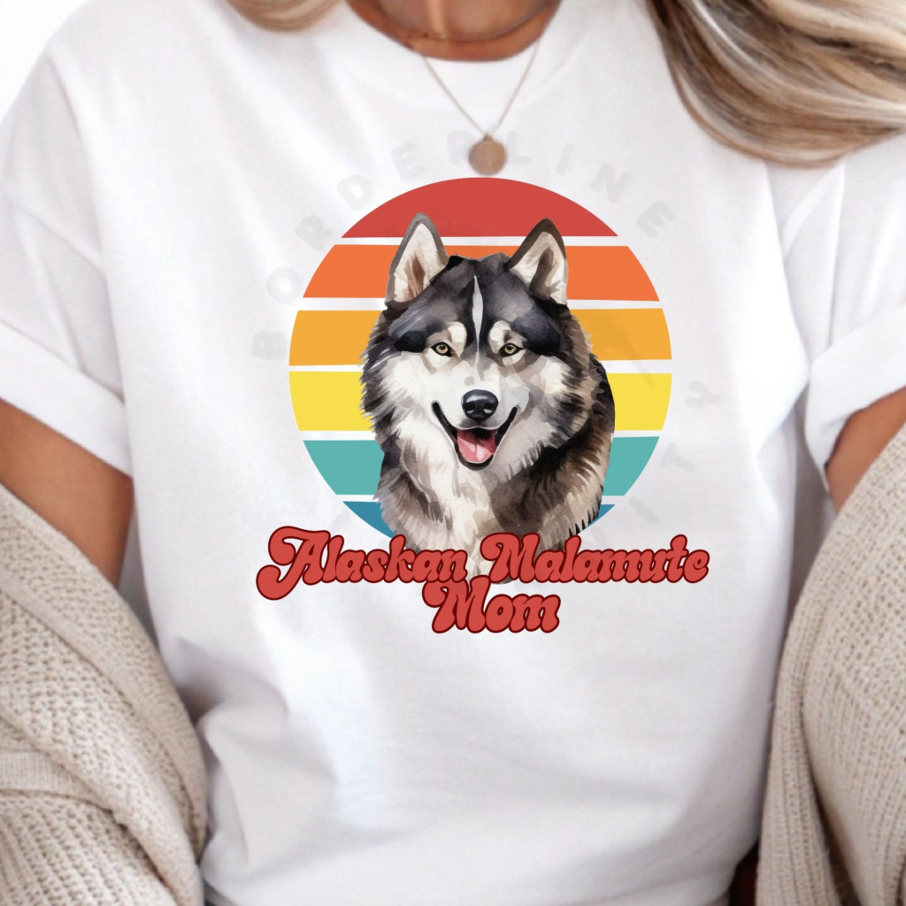 a woman wearing a white tee featuring a retro sunset design and an alaskan malamute with the words alaskan malamute in retro script