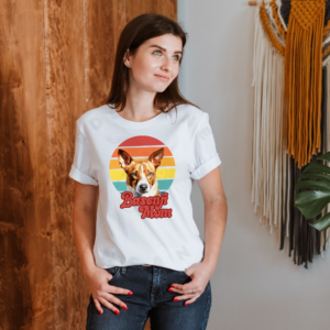 a woman wearing a white tee that features a retro sunset design and a basenji with the words basenji mom in retro script