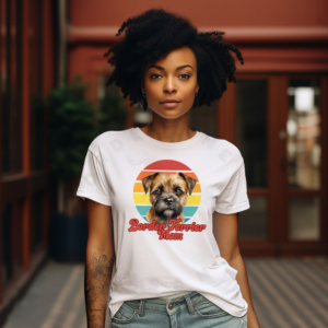 a woman wearing a white tee featuring a retro sunset design with a border terrier and the words border terrier mom in retro script