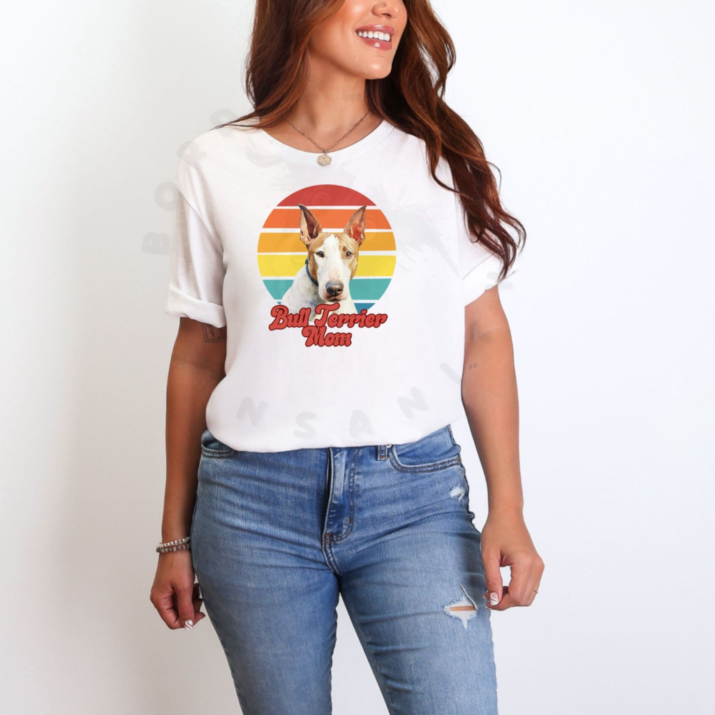 a woman wearing a white tee featuring a retro sunset design with a bull terrier and the words bull terrier mom in retro script