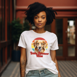 a woman wearing a white tee featuring a retro sunset design with a golden retriever and the words golden retriever mom in retro script