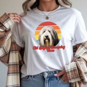 a woman wearing a white tee featuring a retro sunset design with a old english sheepdog and the words old english sheepdog mom in retro script