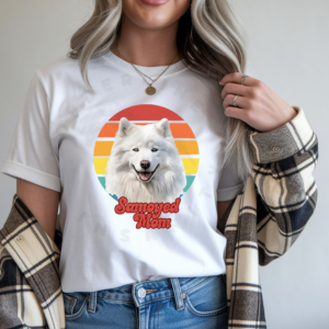 a woman wearing a white tee featuring a retro sunset design and a samoyed that says samoyed mom in retro script