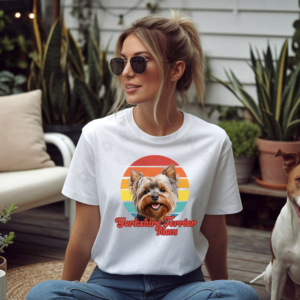 a woman wearing a white tee featuring a retro sunset design with a yorkie and the words yorkshire terrier mom in retro script
