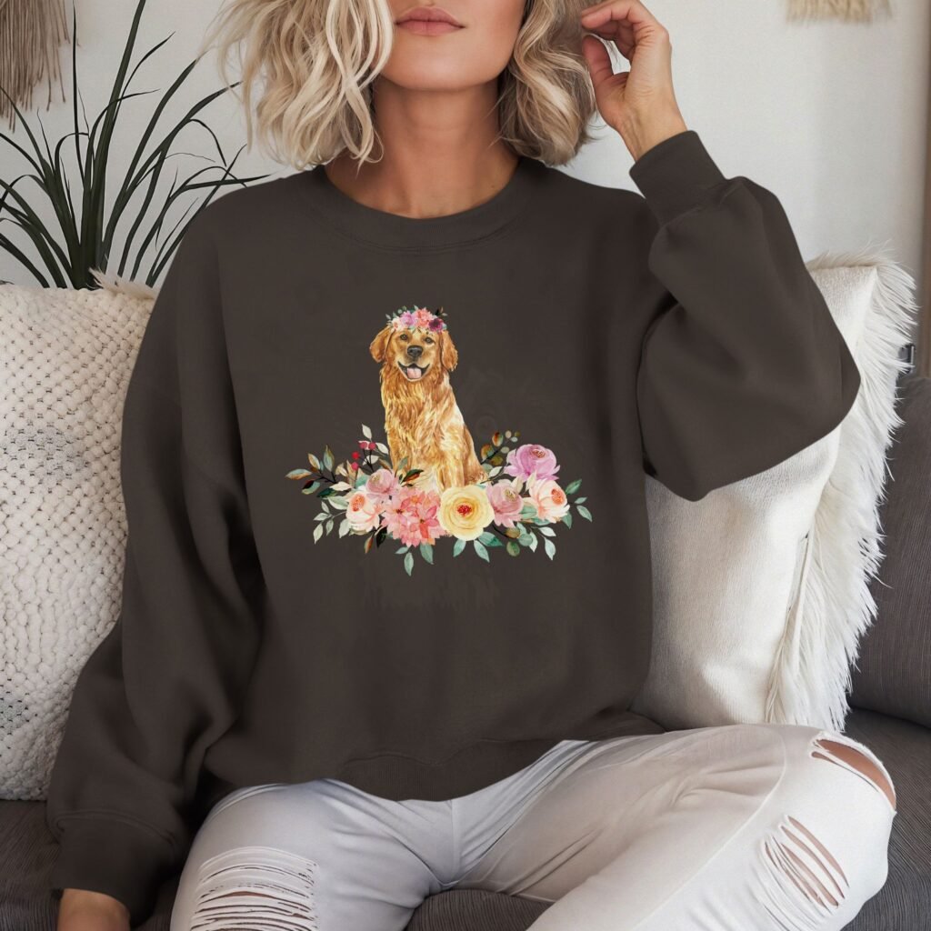 a woman on a sofa wearing a dark brown colored crewneck sweatshirt featuring an image of a golden retriever in watercolor flowers