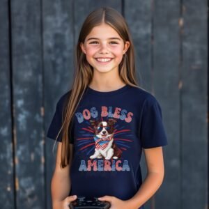 a girl wearing a navy tee featuring a graphic of a cartoon style border collie wearing an american flag bandana with the words dog bless america in red and blue