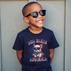 a boy wearing a navy tee featuring a graphic of a cartoon style French Bulldog wearing an american flag bandana with the words dog bless america in red and blue
