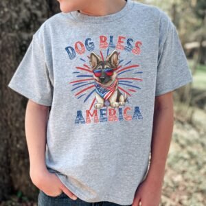 a boy wearing a sport grey tee featuring a graphic of a cartoon style german shepherd wearing an american flag bandana with the words dog bless america in red and blue