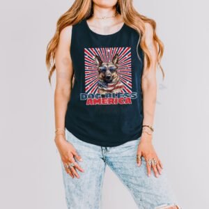 a woman wearing a navy tank with a patriotic background and an image of a german shepherd in an american flag bandana and sunglasses that says dog bless america