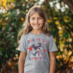 a girl wearing a sport grey tee featuring a graphic of a cartoon style schnauzer wearing an american flag bandana with the words dog bless america in red and blue