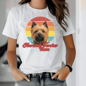 a woman wearing a white tee featuring a retro sunset design with a norwich terrier and the words norwich terrier mom in retro script